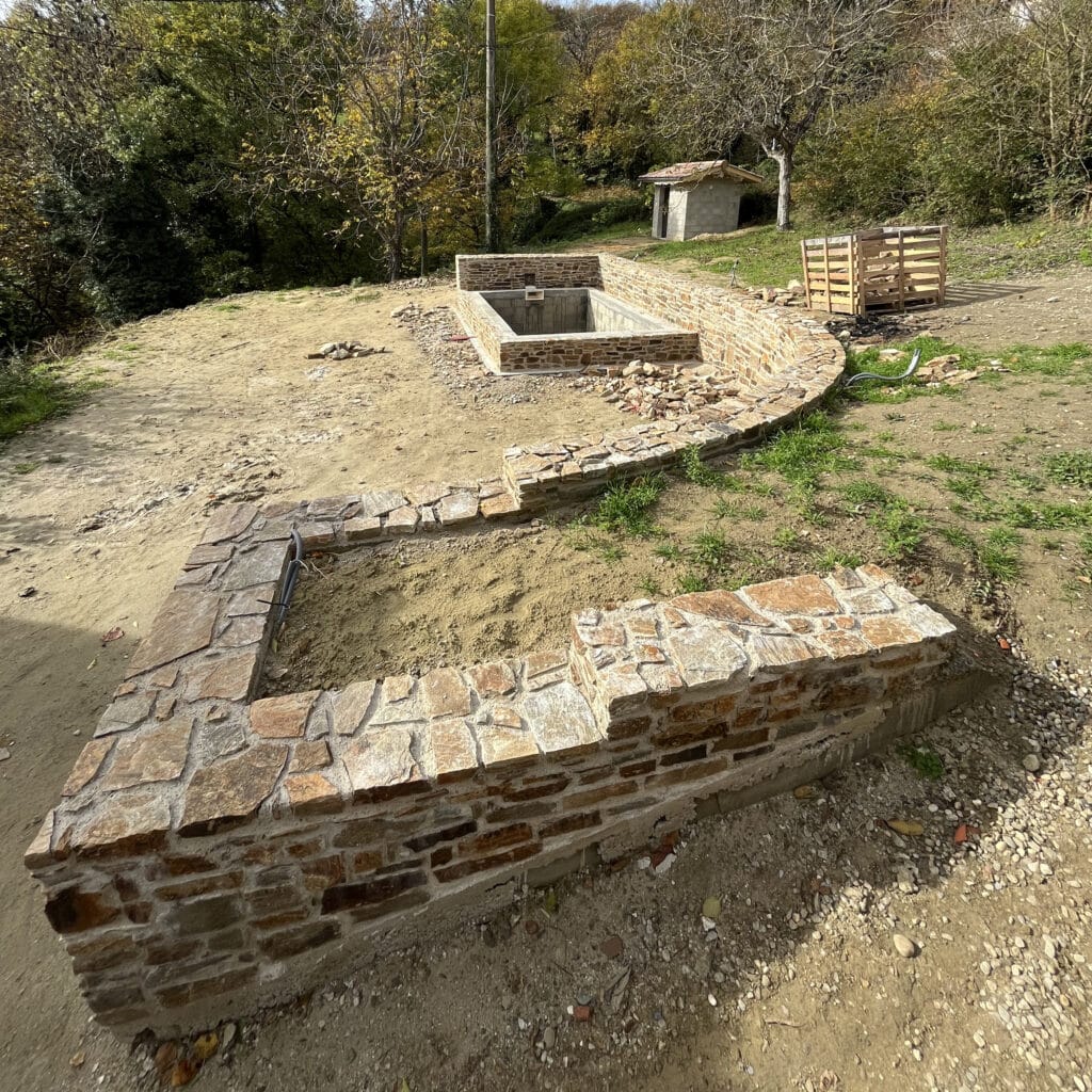 Construction de murs en pierre et bassin de jardin Aménagement paysager avec murs en pierre naturelle et bassin rectangulaire en cours de construction dans un jardin.